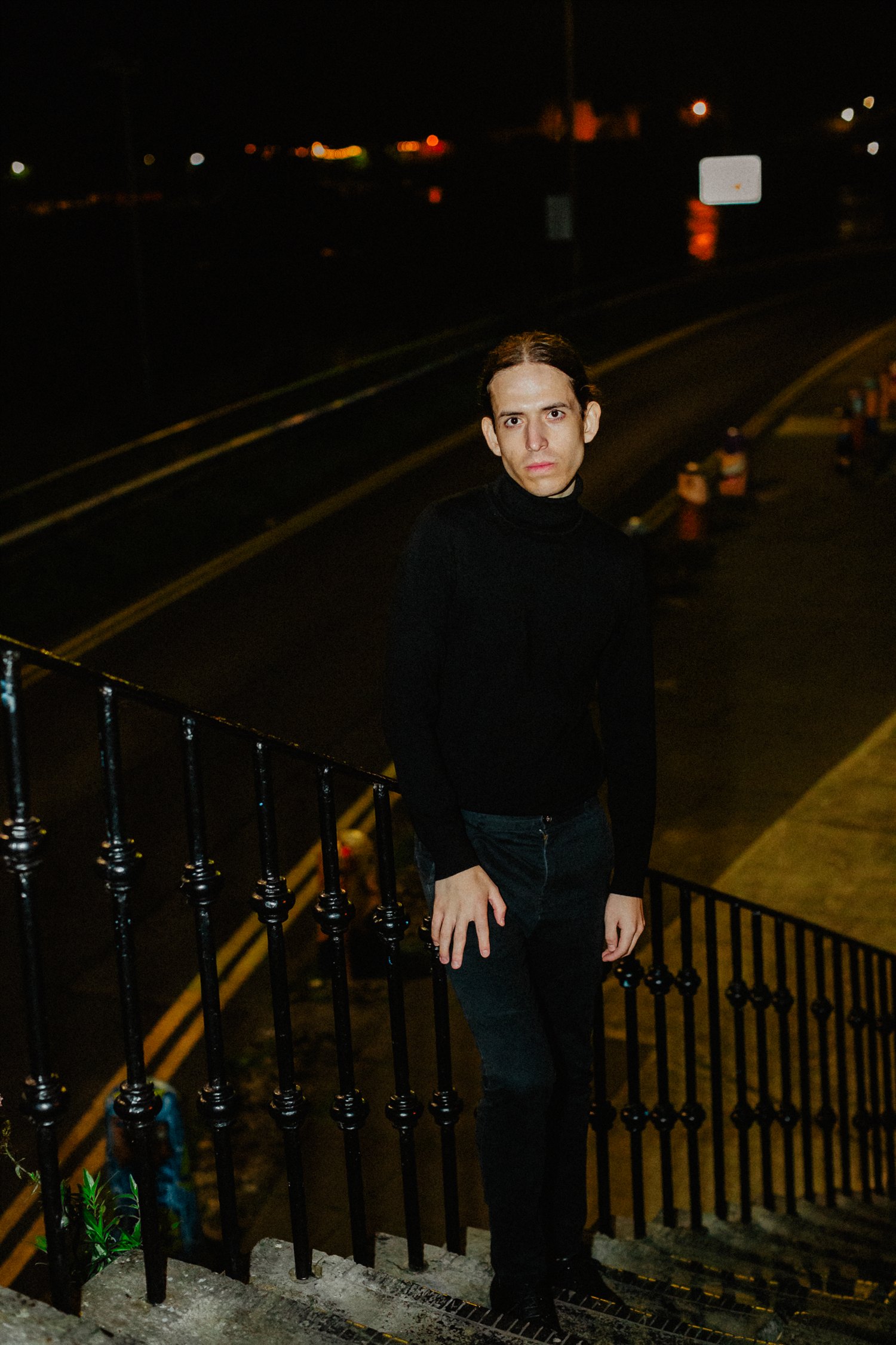 Sebastian Graysen standing on steps above a road at night, looking at the camera